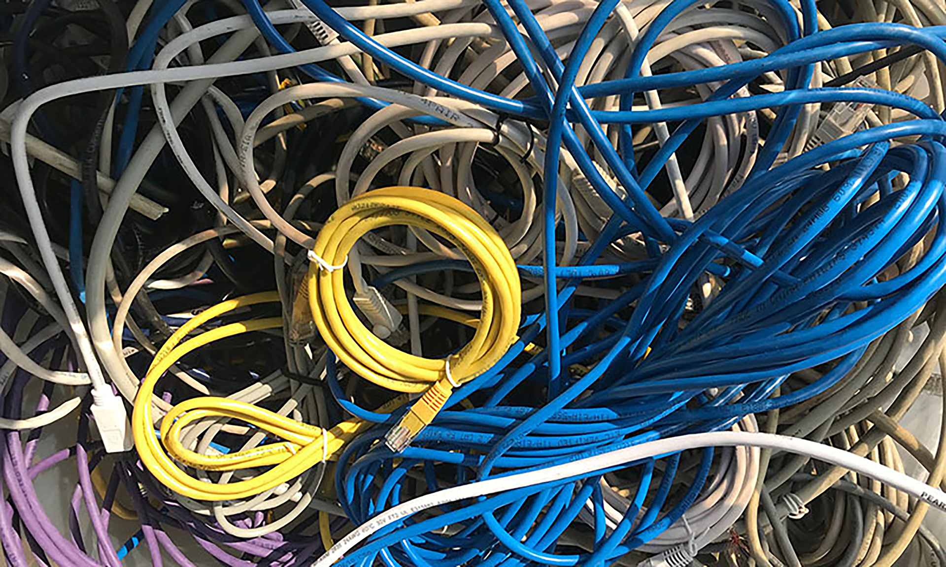 A tangled mass of white, purple, yellow, and blue cords.