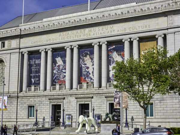 Exterior view of the Asian Art Museum with banners and a large sculpture in the foreground